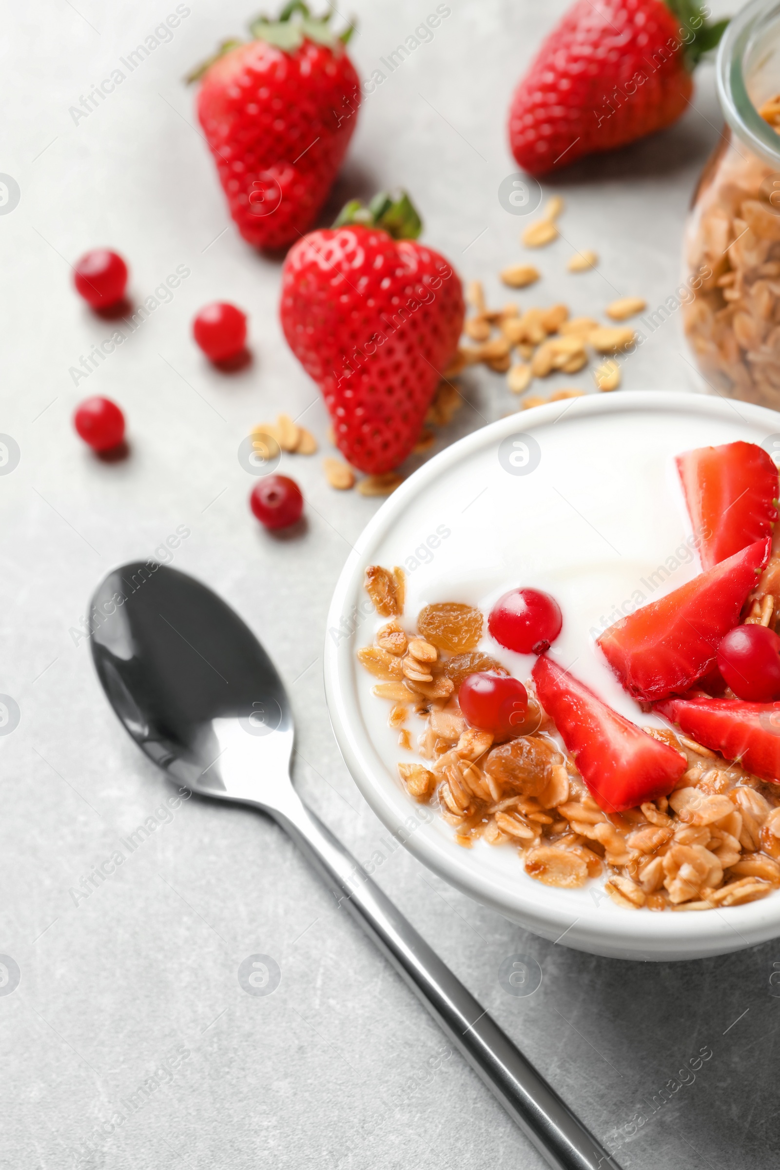 Photo of Bowl with yogurt, berries and granola on table