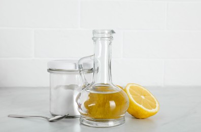 Vinegar, baking soda and lemon on white marble table. Eco friendly natural detergents
