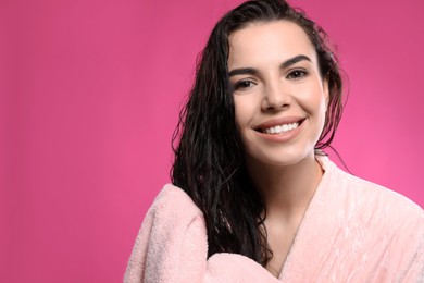Happy young woman drying hair with towel after washing on pink background. Space for text