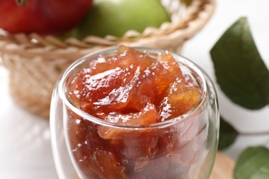 Photo of Glass of delicious apple jam against blurred background, closeup