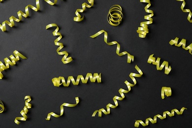 Photo of Yellow serpentine streamers on black background, flat lay