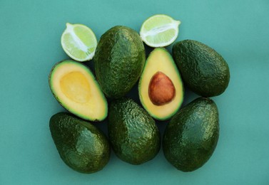 Tasty whole and cut avocados with lime on turquoise background, flat lay