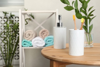 Photo of Holder with bamboo toothbrushes on table against blurred background