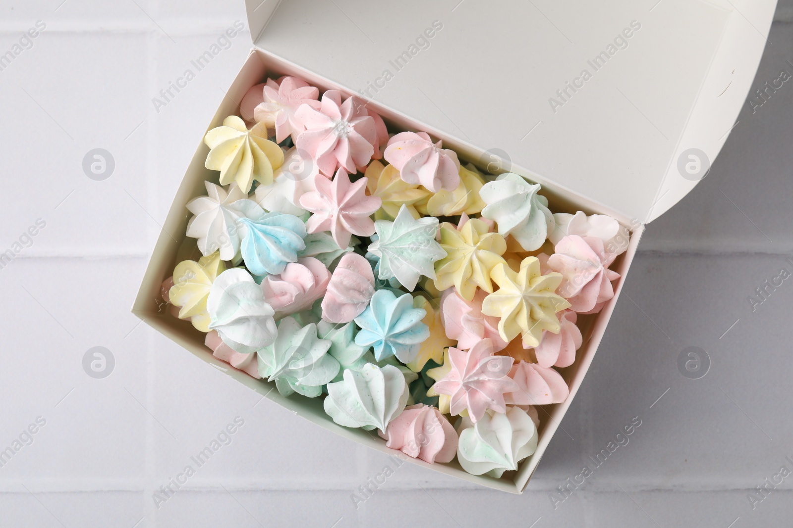 Photo of Tasty meringue cookies on white tiled table