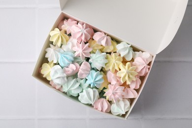 Photo of Tasty meringue cookies on white tiled table