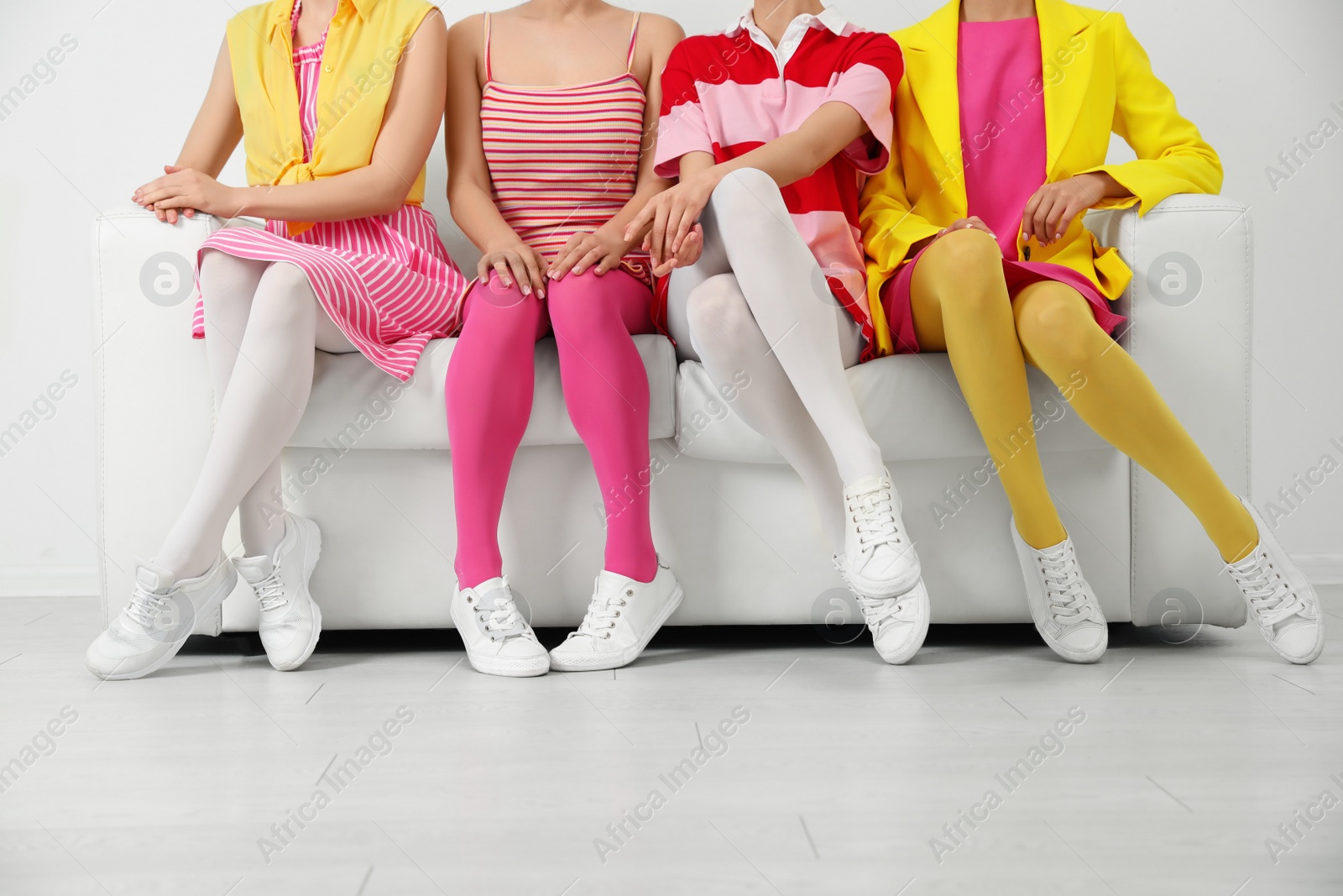 Photo of Women wearing colorful tights sitting on sofa indoors, closeup