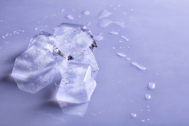 Photo of Transparent ice cubes on color mirror surface. Space for text