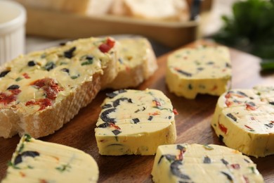 Photo of Tasty butter with olives, chili pepper, parsley and bread on table, closeup