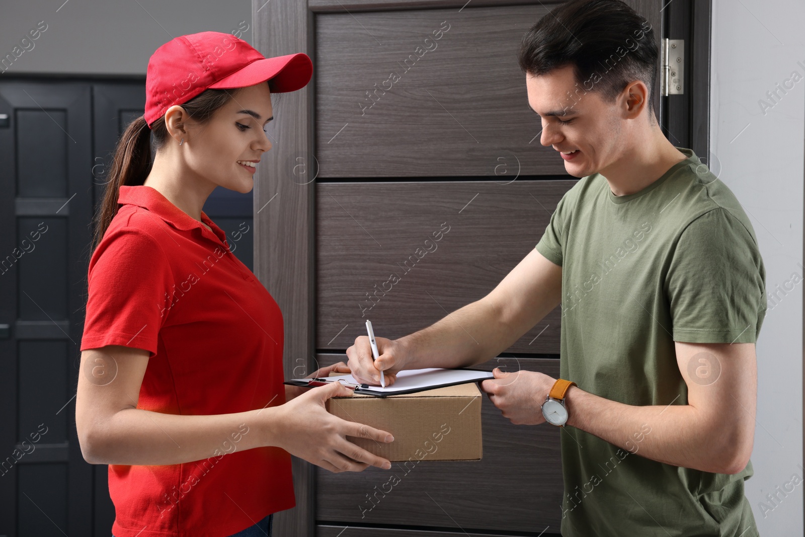 Photo of Man signing for delivered parcel from courier indoors