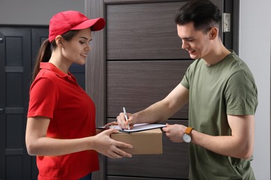 Photo of Man signing for delivered parcel from courier indoors