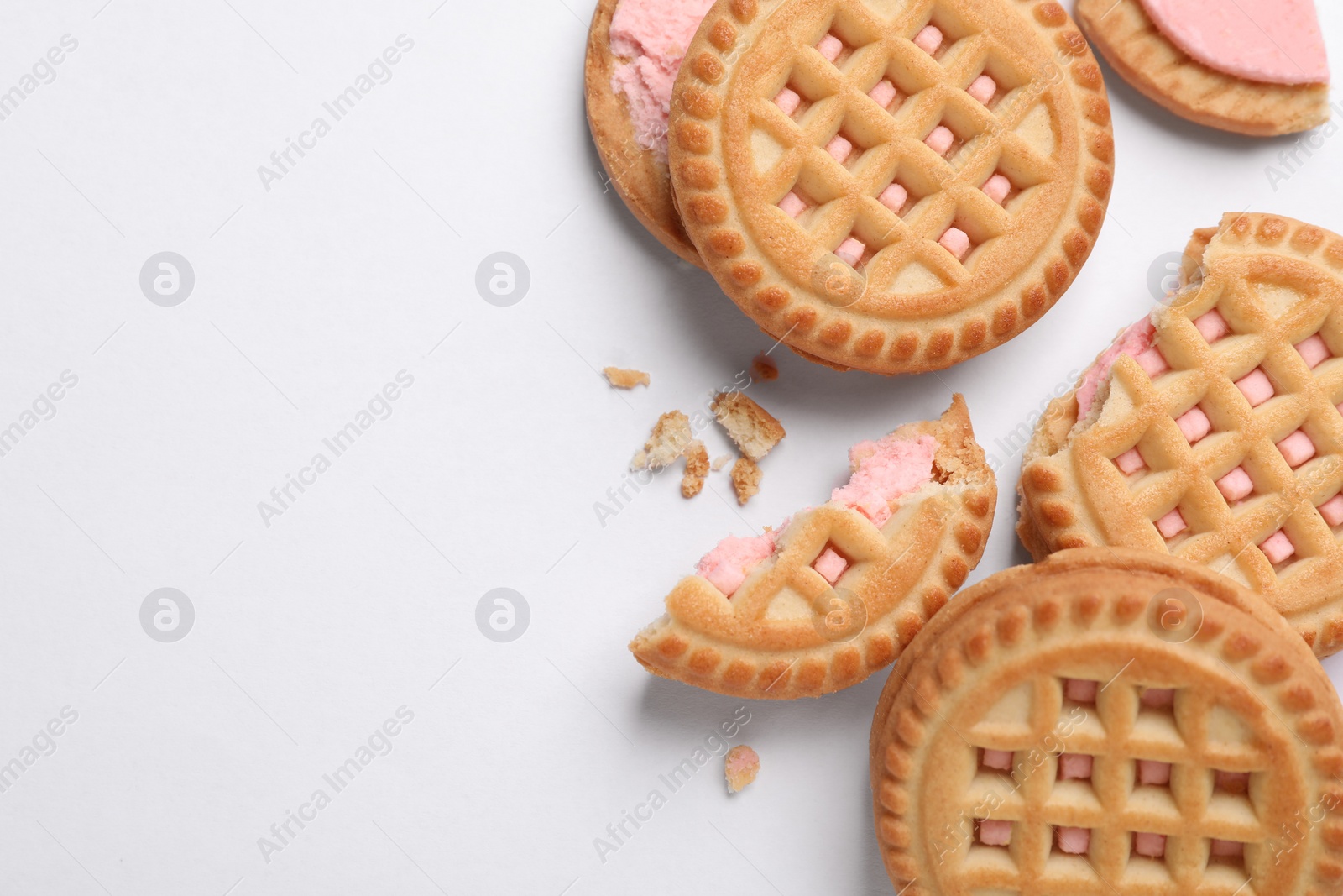 Photo of Tasty sandwich cookies with cream on white background, flat lay. Space for text