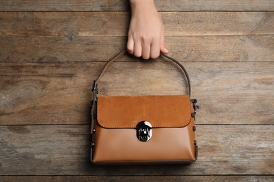 Woman holding small bag on wooden background, top view