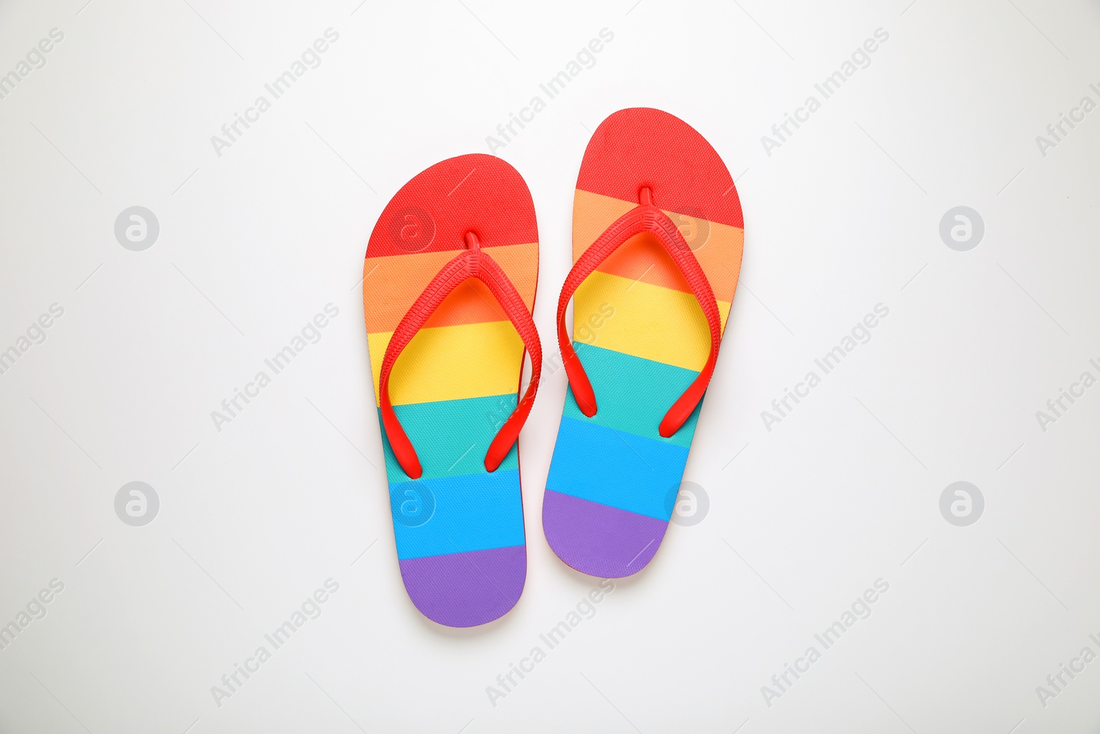 Photo of Stylish rainbow flip flops on white background, top view