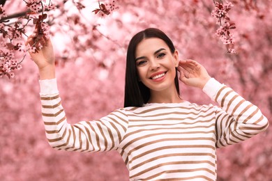 Pretty young woman in park with blooming trees. Spring look
