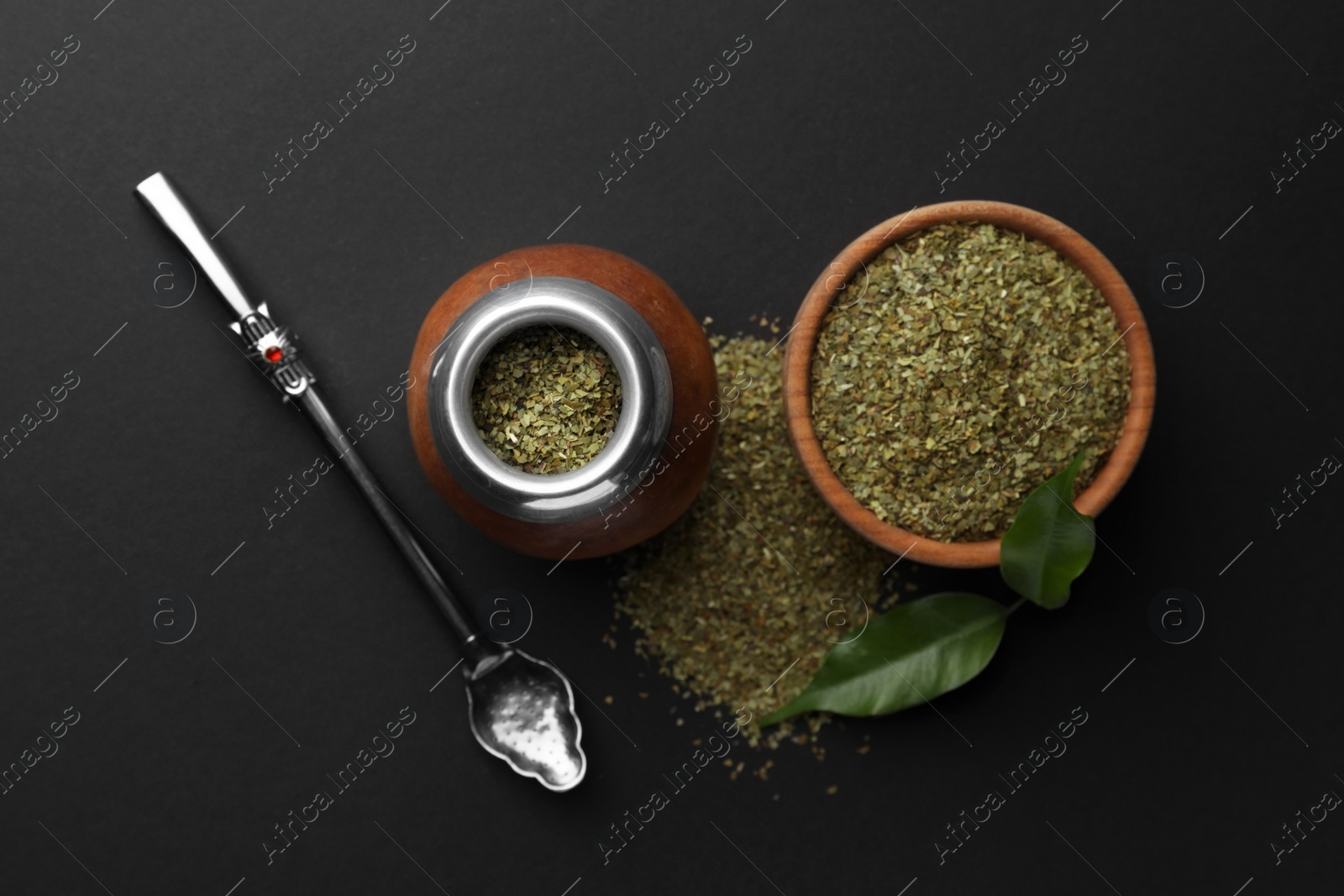 Photo of Calabash with mate tea and bombilla on black table, flat lay