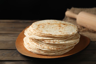 Photo of Many tasty homemade tortillas and rolling pin on wooden table