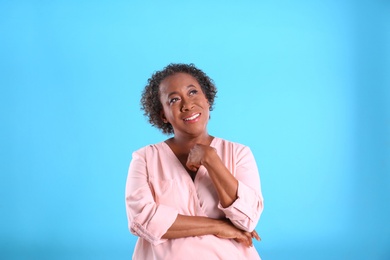 Portrait of happy African-American woman on light blue background