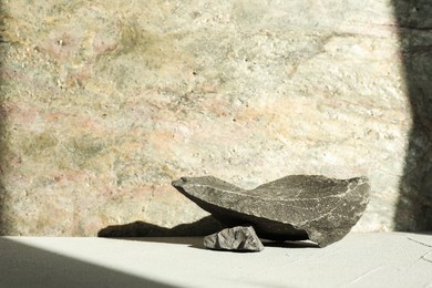 Photo of Presentation of product. Podium made of stones on light textured table. Space for text