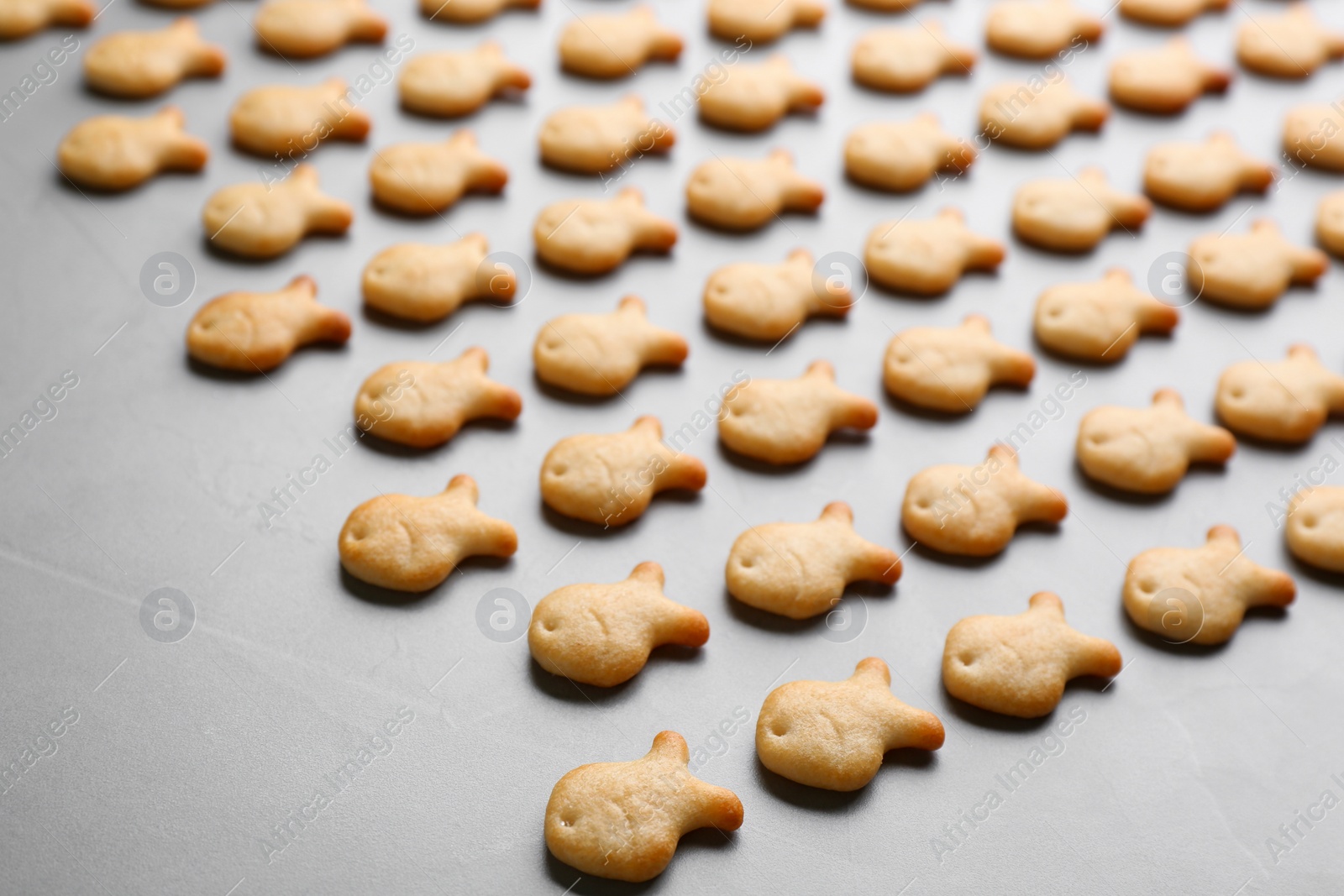 Photo of Delicious goldfish crackers on grey table, closeup