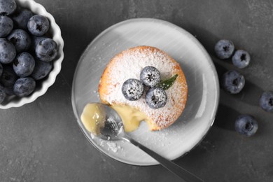 Photo of Tasty vanilla fondant with white chocolate and blueberries on grey table, flat lay