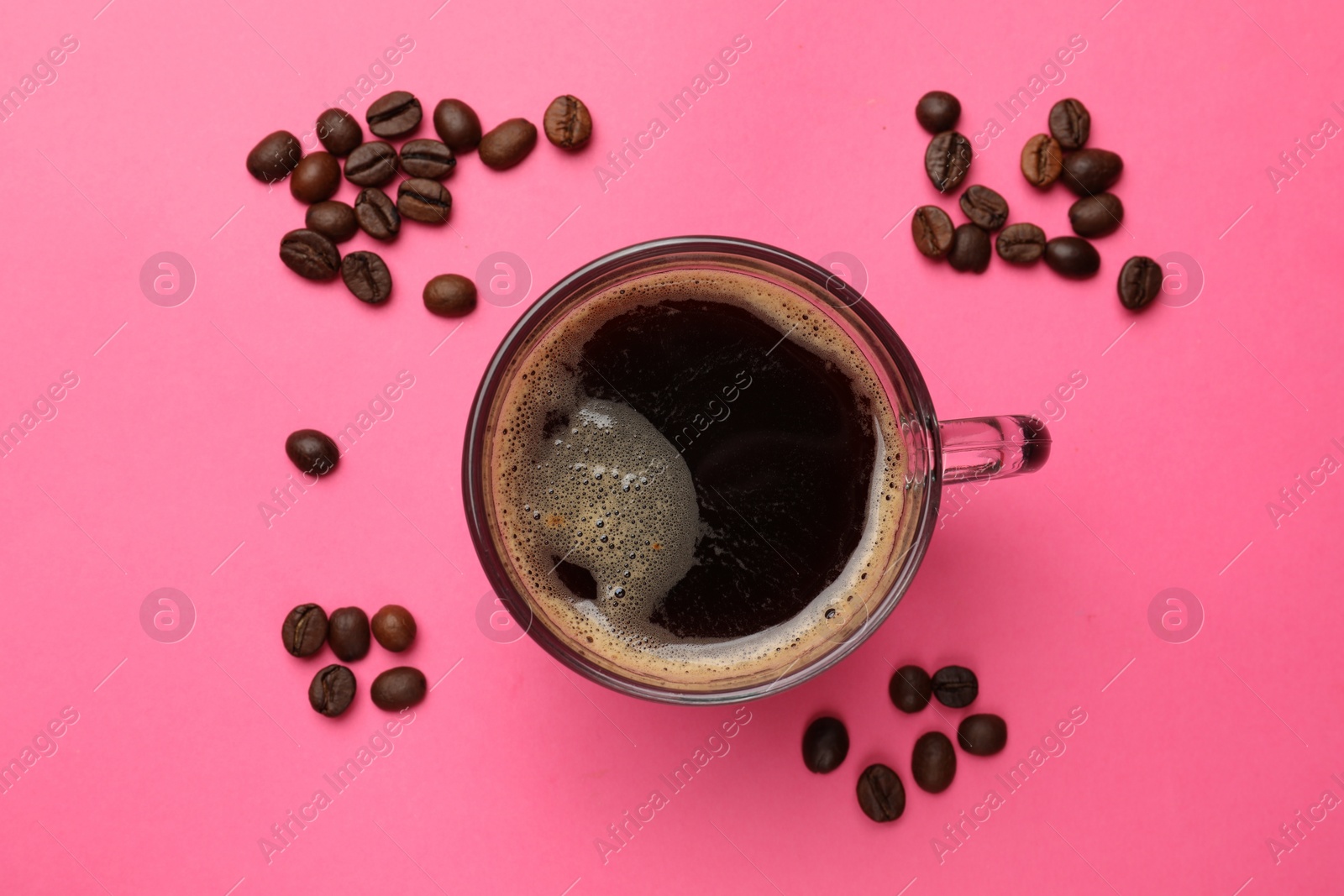 Photo of Fresh coffee in cup and roasted beans on pink background, top view