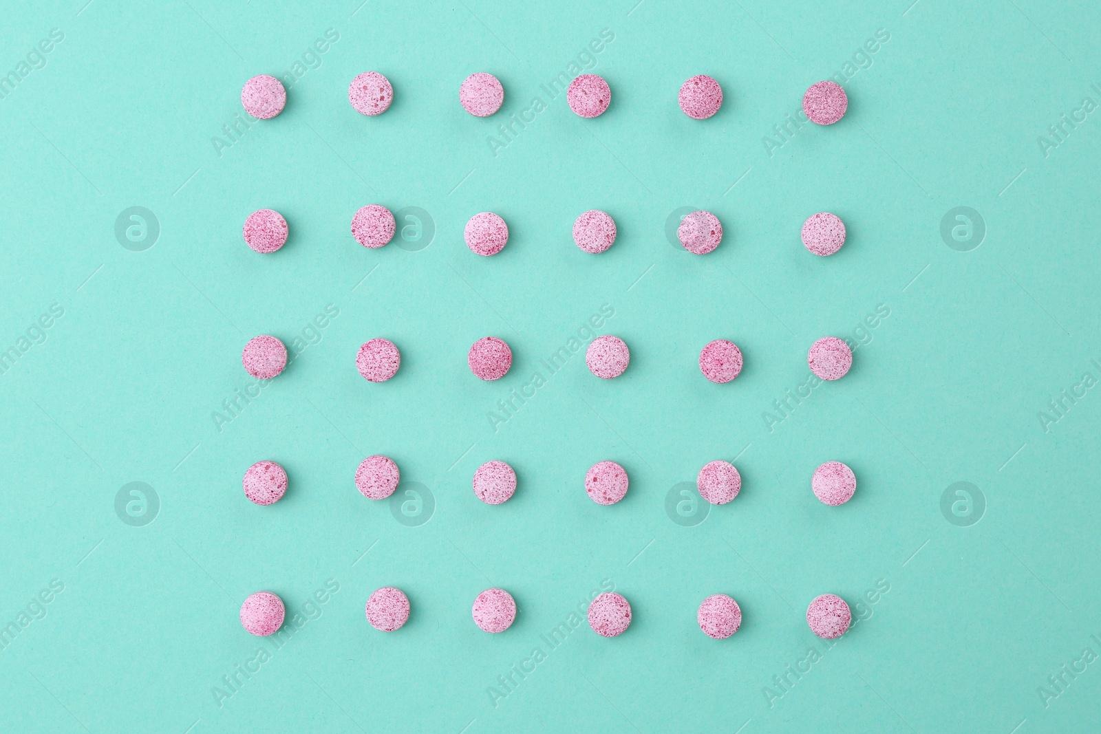 Photo of Many pink vitamin pills on turquoise background, flat lay