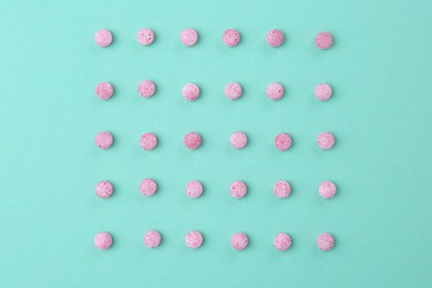 Photo of Many pink vitamin pills on turquoise background, flat lay