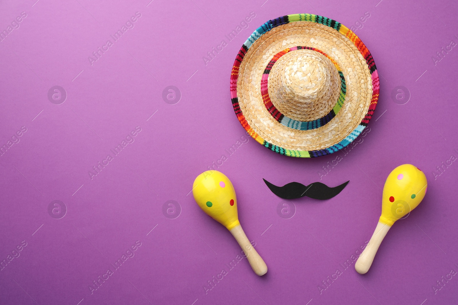 Photo of Mexican sombrero hat, fake mustache and maracas on purple background, flat lay. Space for text