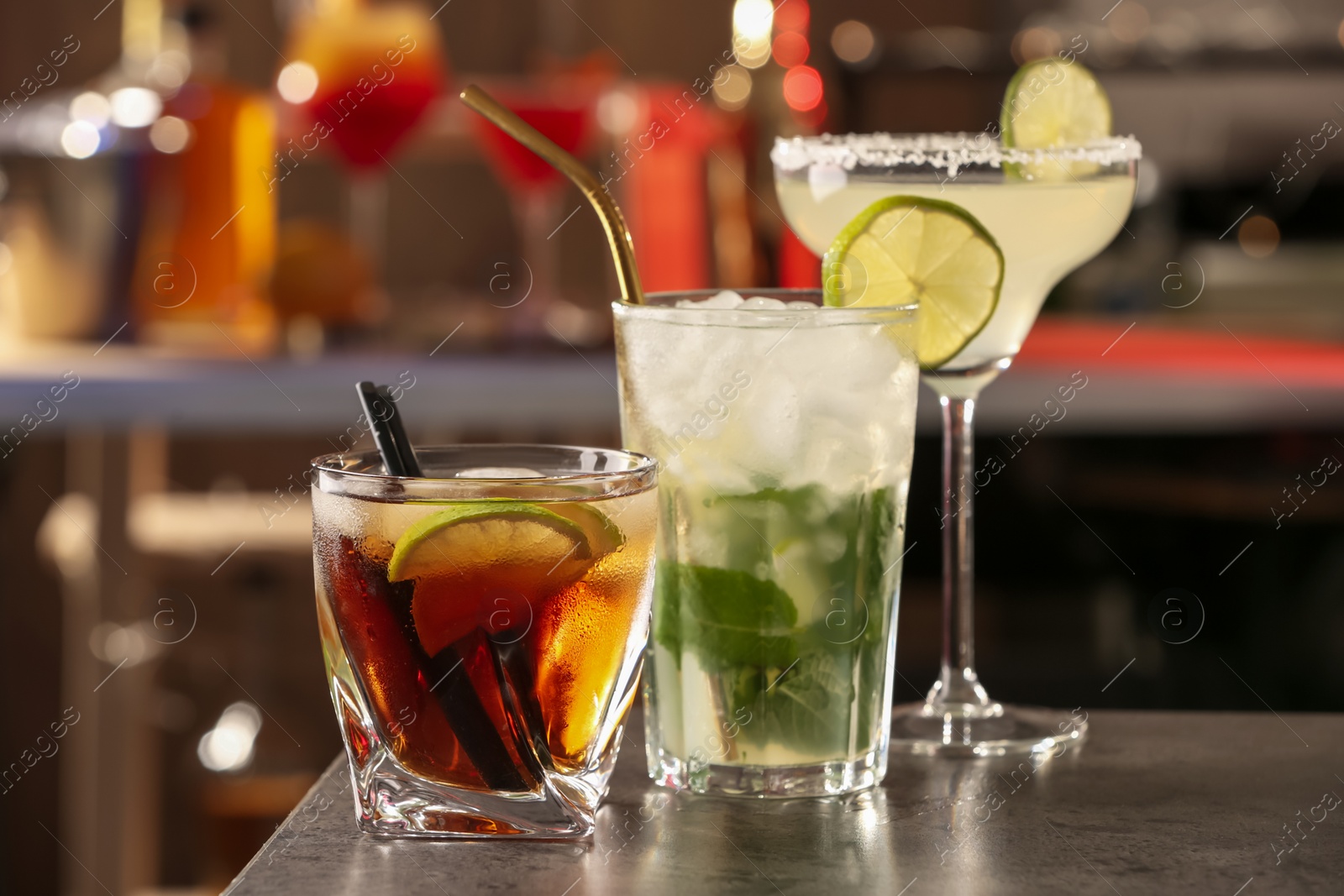 Photo of Different delicious cocktails on grey table in bar