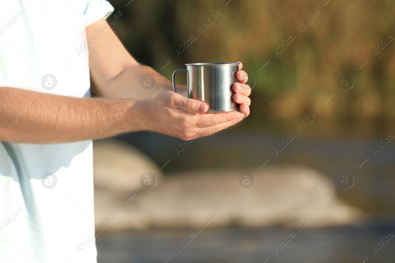 Photo of Male camper with metal mug outdoors, closeup. Space for text