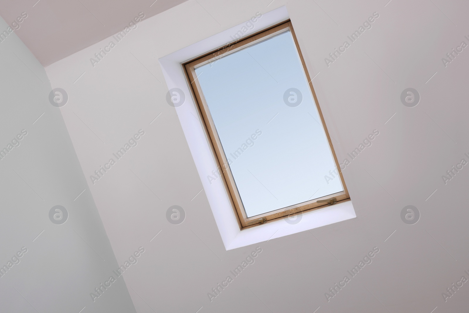 Photo of Skylight roof window and lamps on slanted ceiling in attic room, low angle view