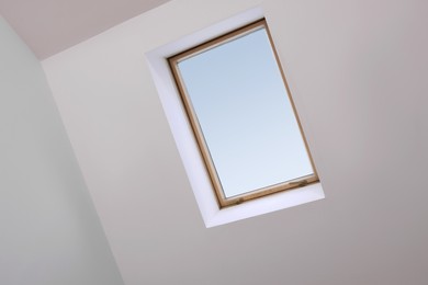 Photo of Skylight roof window and lamps on slanted ceiling in attic room, low angle view