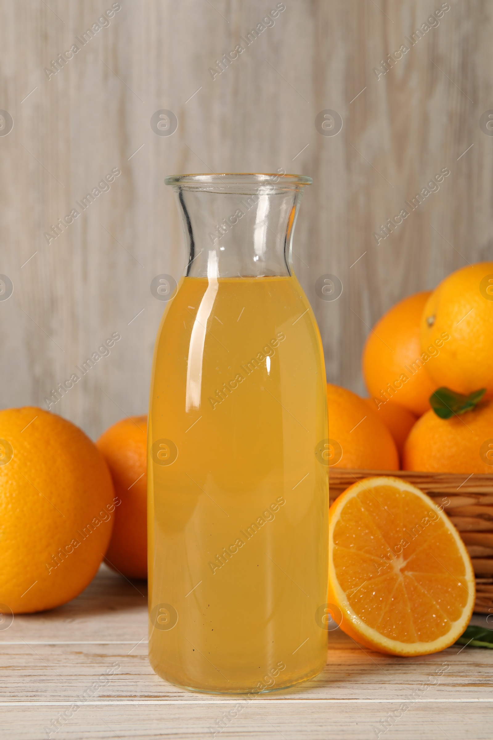 Photo of Many ripe oranges and fresh juice on light wooden table