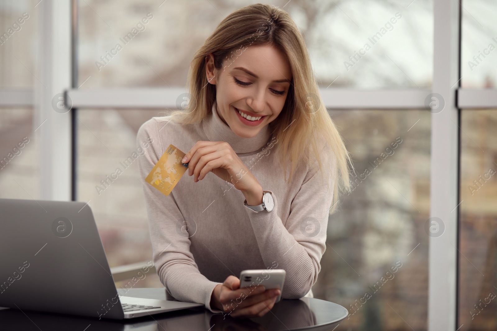 Photo of Woman with credit card using smartphone for online shopping indoors