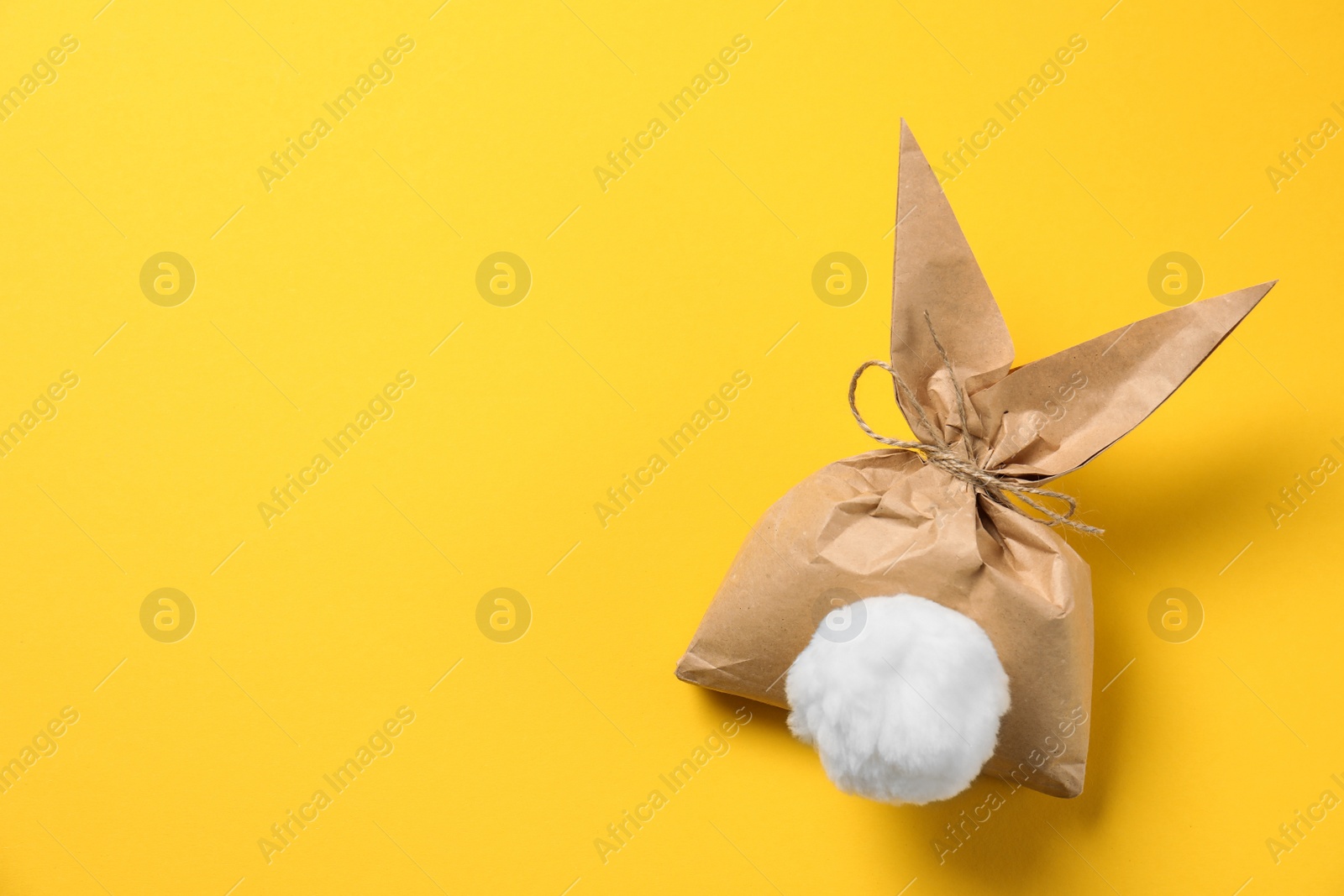 Photo of Creative Easter bunny gift bag on color background, top view with space for text