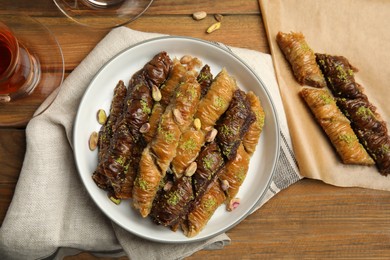 Delicious sweet baklava with pistachios and hot tea on wooden table, flat lay