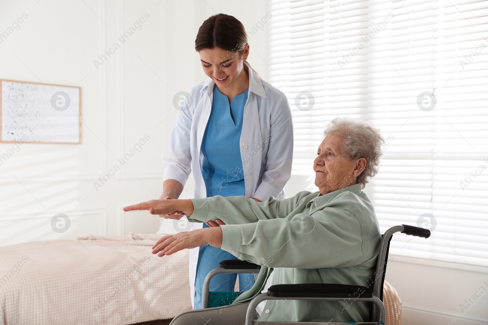 Photo of Senior woman in wheelchair doing physical exercise indoors. Home health care service