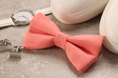 Photo of Stylish pink bow tie, wristwatch, shoes and cufflinks on light grey background