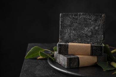 Photo of Stack of natural tar soap on black table