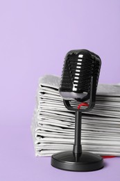 Photo of Newspapers and vintage microphone on light violet background. Journalist's work