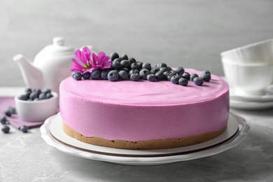 Photo of Plate with tasty blueberry cake on light grey table