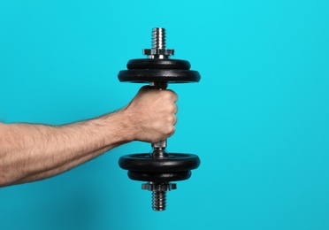 Photo of Male athlete holding metal dumbbell on color background. Space for text