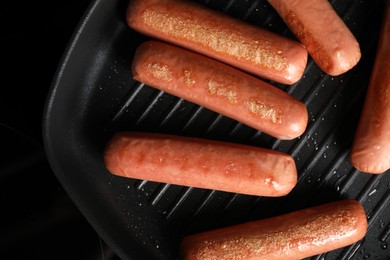 Photo of Cooking vegan sausages in grill pan on cooktop, top view