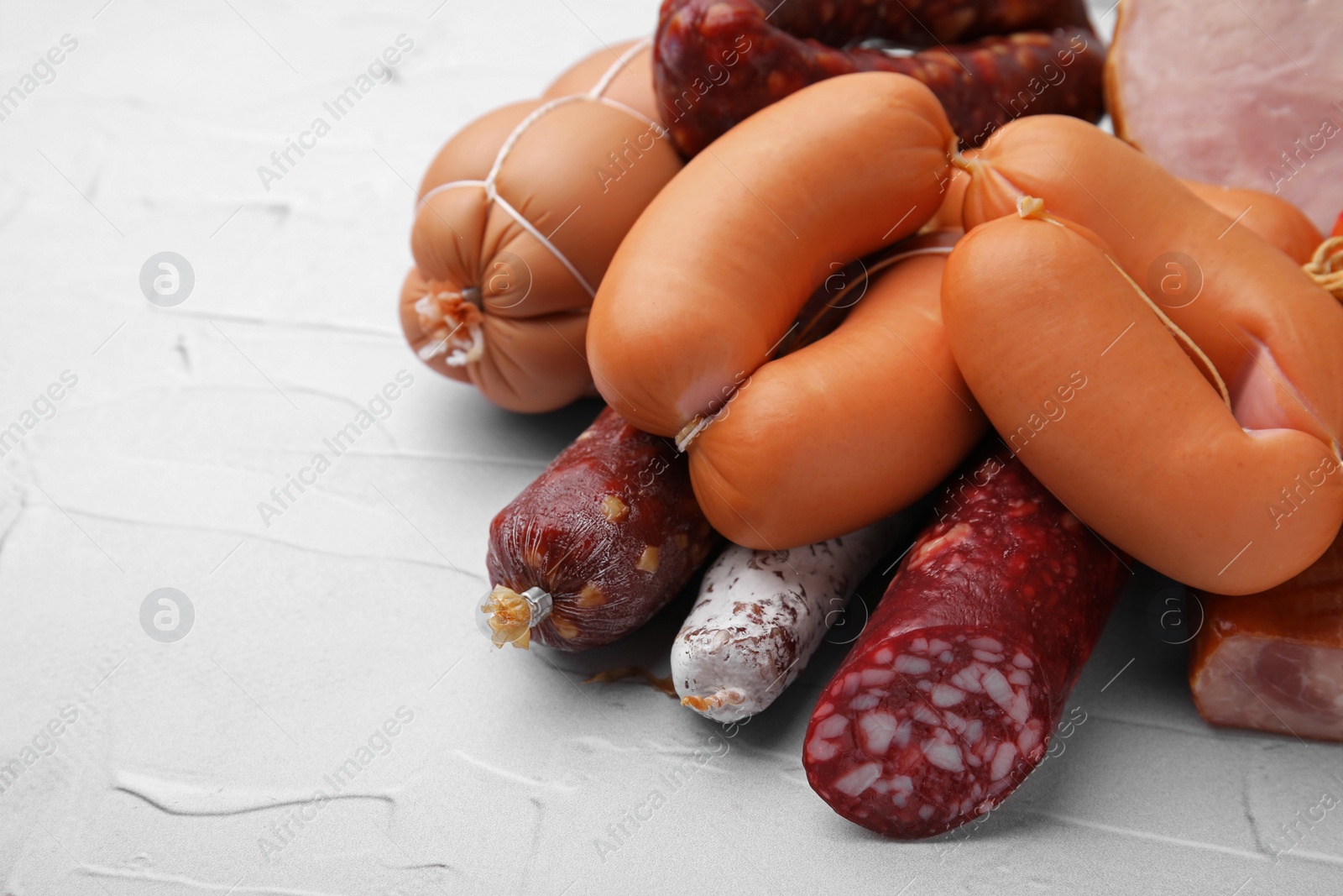 Photo of Different types of sausages on light textured table, closeup. Space for text