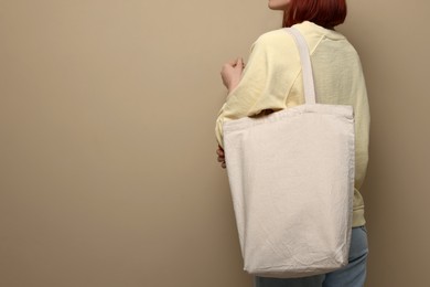 Woman with eco bag on beige background, closeup. Space for text