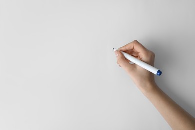 Woman holding color marker on white background, top view