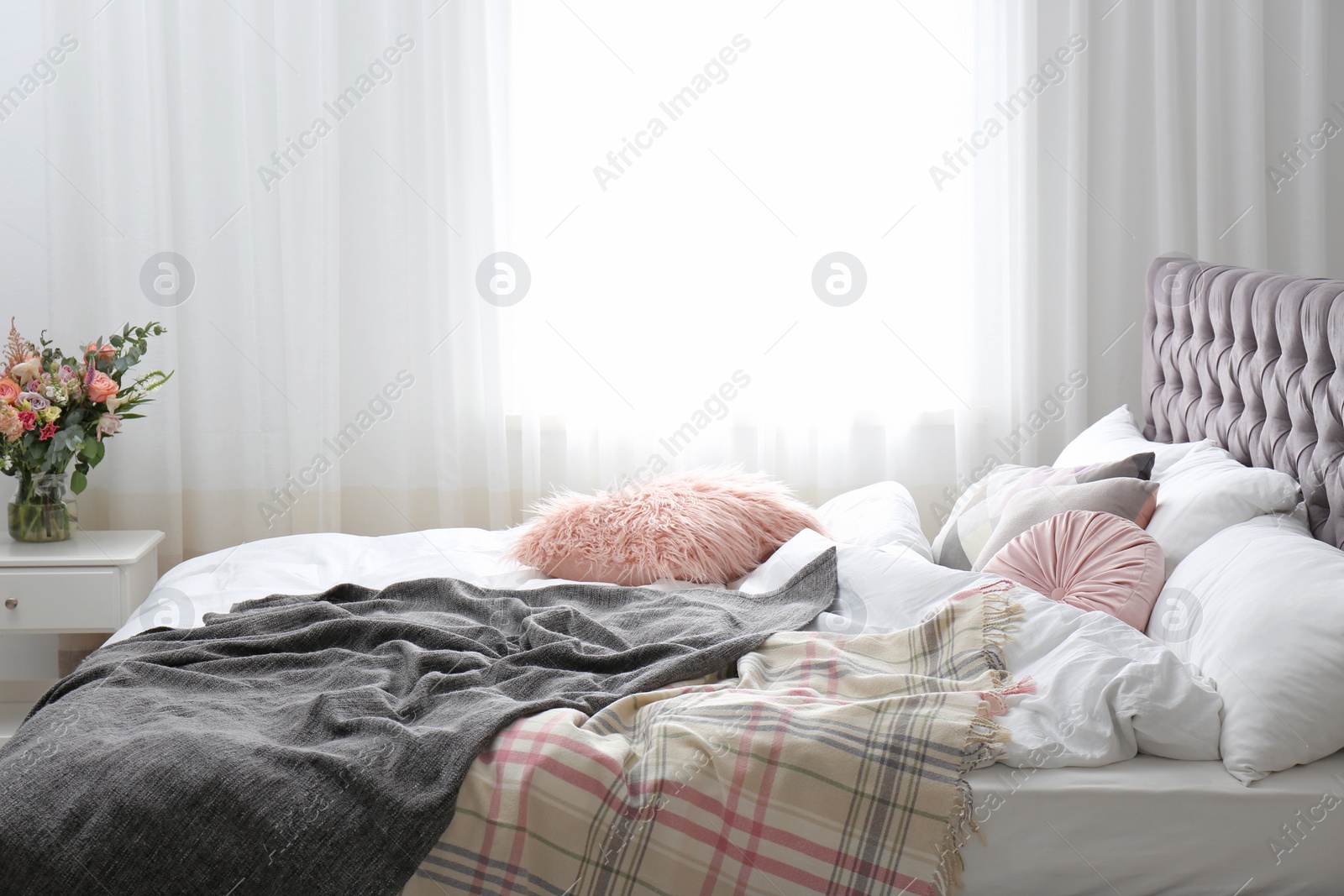 Photo of Comfortable bed with plaids and pillows in room