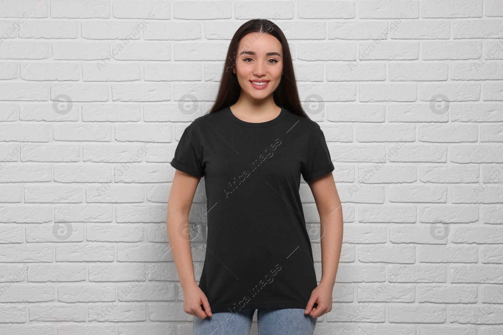 Photo of Woman wearing stylish black T-shirt near white brick wall