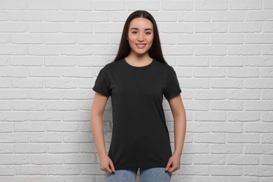 Woman wearing stylish black T-shirt near white brick wall