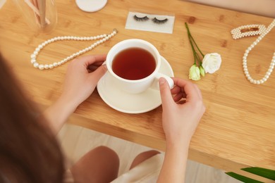 Photo of Bride with cup of tea at dressing table indoors, closeup. Wedding day